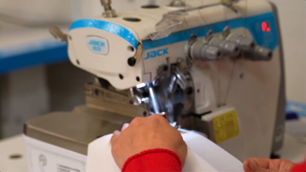 MG Sportswear machinist stitching fabric on an industrial sewing machine, highlighting our in‑house manufacturing