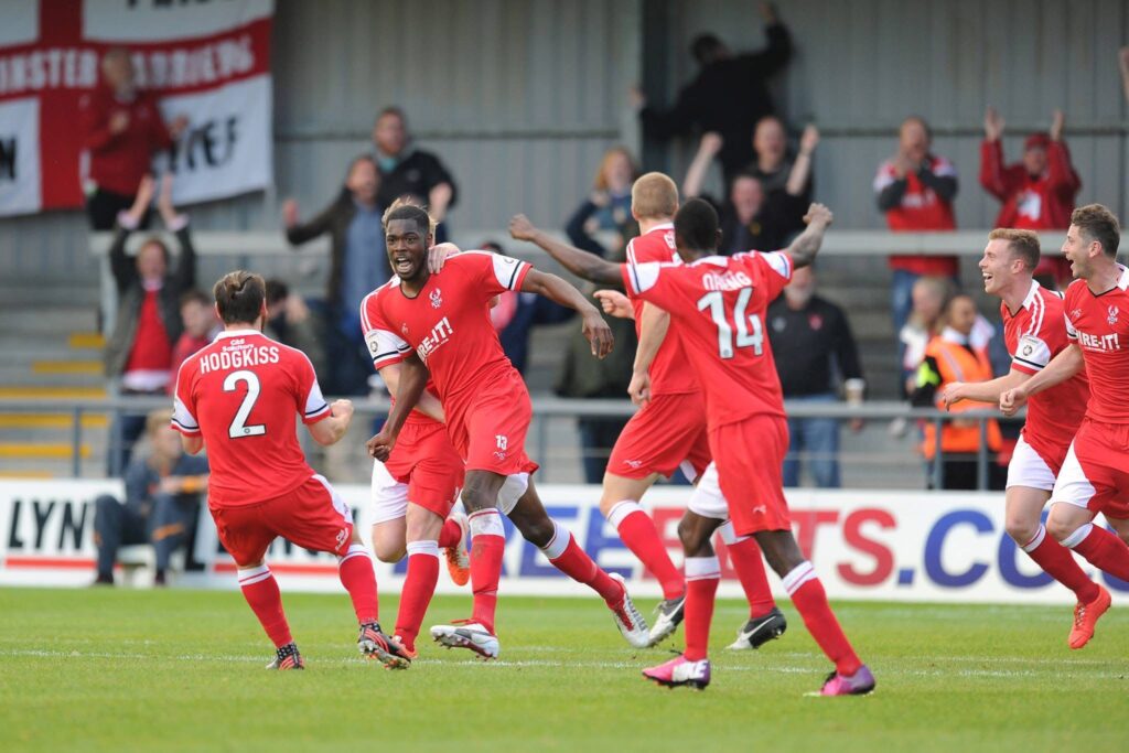 Kidderminster Harriers players celebrate a goal in their custom MG Sportswear Football Kit